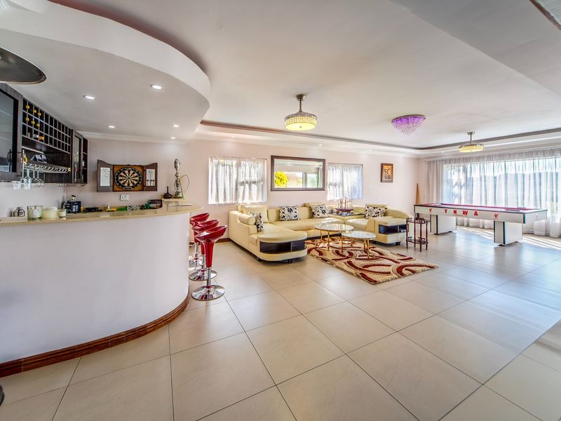 Spacious open-plan living area featuring a built-in bar counter, tiled flooring, and recessed ceiling lighting, offering a versatile entertainment space.
