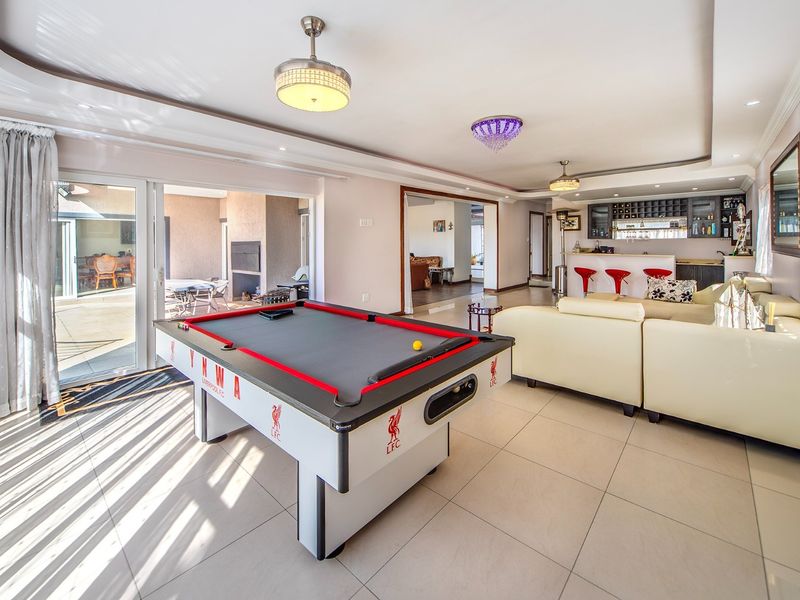 Spacious open-plan living area featuring tiled floors, recessed ceiling lighting, and a built-in bar, with seamless access to an outdoor patio.