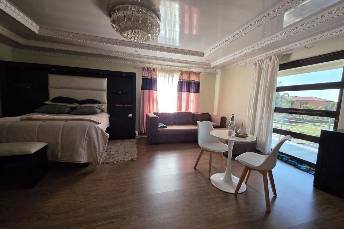 Spacious bedroom featuring laminate flooring, decorative ceiling cornices, recessed lighting, and large sliding glass doors providing access to the exterior.
