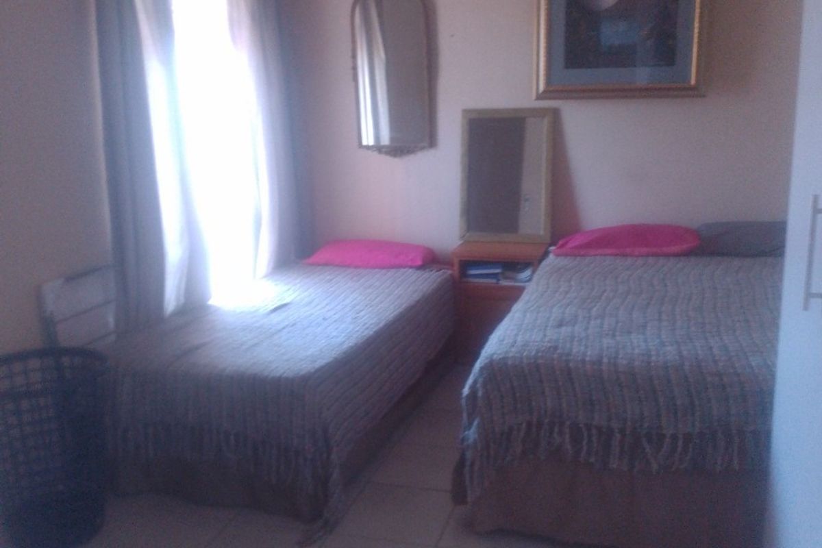 A bedroom featuring tiled flooring and a ceiling fan, with natural light entering through the window.
