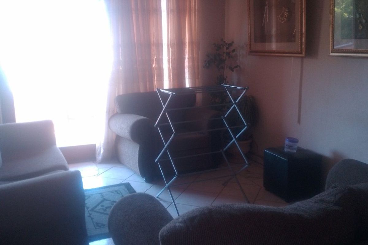 A living room area featuring tiled flooring, a ceiling fan, and a sliding glass door providing natural light.