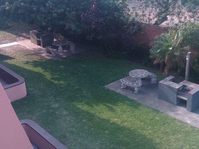 Communal garden area featuring built-in braai facilities and concrete seating areas set within a landscaped lawn.