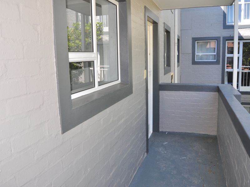 A functional apartment balcony featuring painted brick walls and a concrete floor, providing an outdoor transition space.