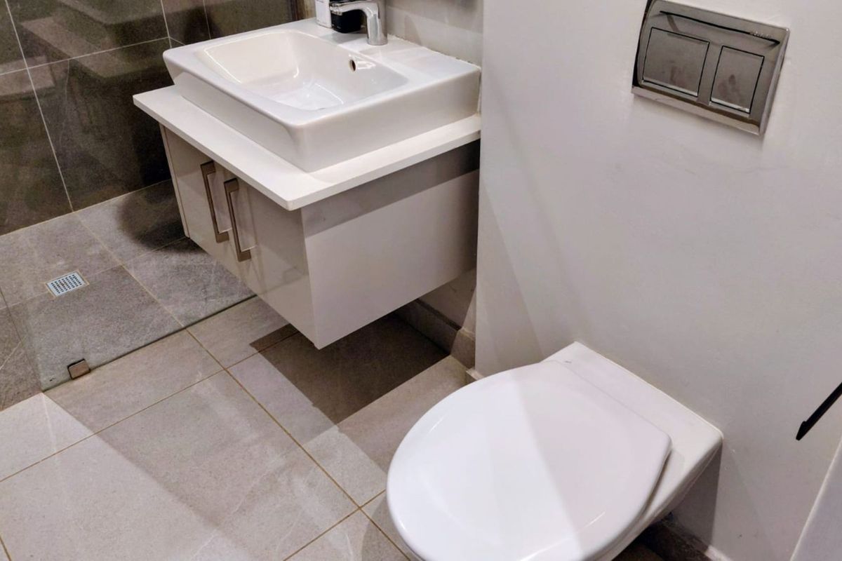 Modern bathroom featuring a wall-mounted vanity with vessel sink, wall-hung toilet with concealed cistern, and a tiled walk-in shower area.