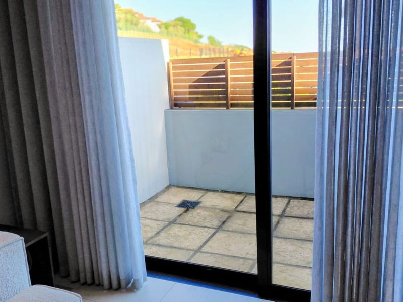 A private paved patio area featuring a timber slat privacy screen and sliding glass door access from the interior.