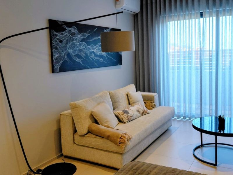 A well-maintained living room featuring tiled flooring, a split-system air conditioner, and large sliding glass doors with floor-to-ceiling curtains for natural light.