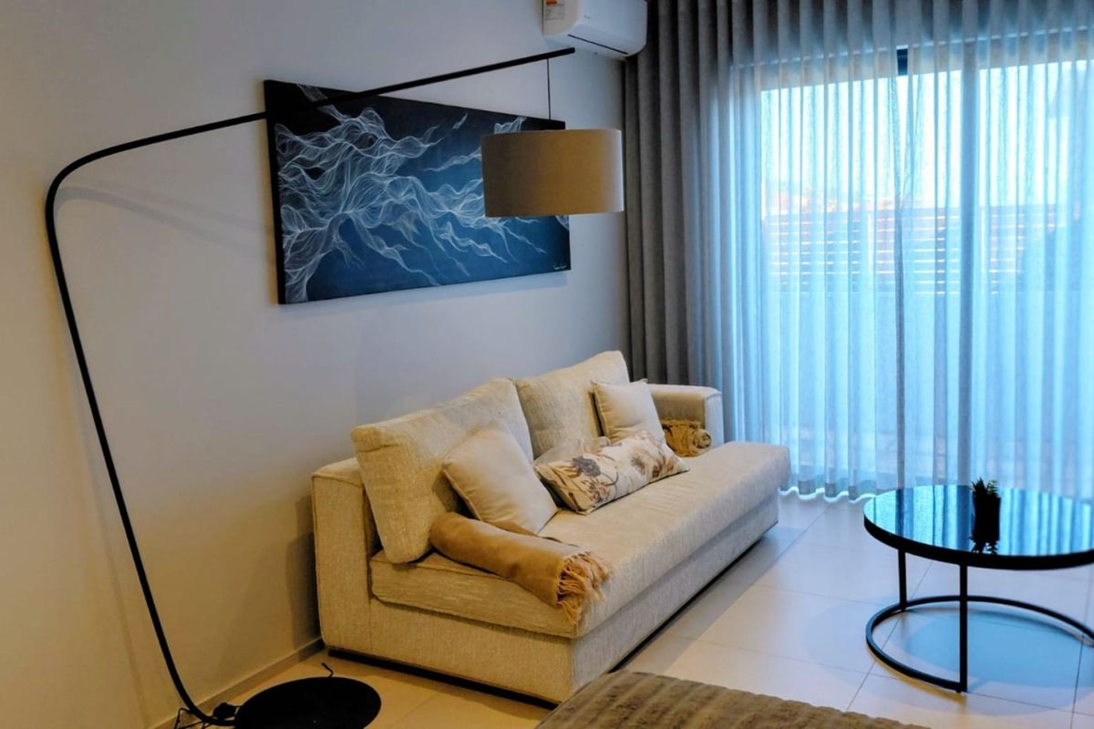A well-maintained living room featuring tiled flooring, a split-system air conditioner, and large sliding glass doors with floor-to-ceiling curtains for natural light.