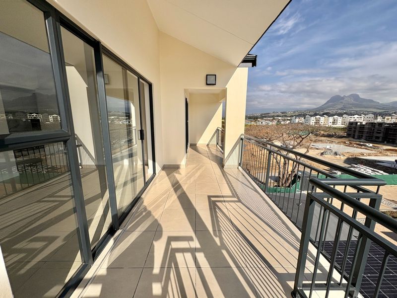 A spacious, modern balcony featuring tiled flooring, a secure metal balustrade, and large sliding glass doors with scenic mountain views.