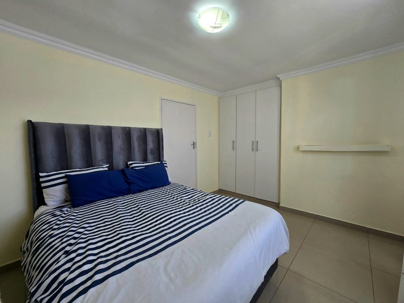 A functional bedroom featuring tiled flooring, built-in cupboards, and neutral wall finishes, providing a clean and practical living space.