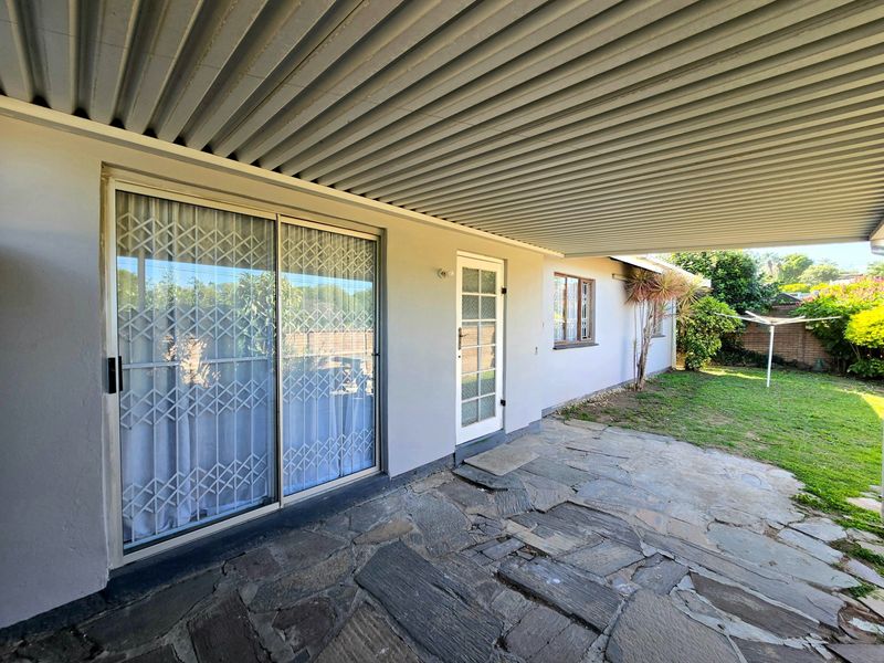 Covered patio area featuring flagstone paving, a sliding glass door with security gate, and direct access to the rear garden.