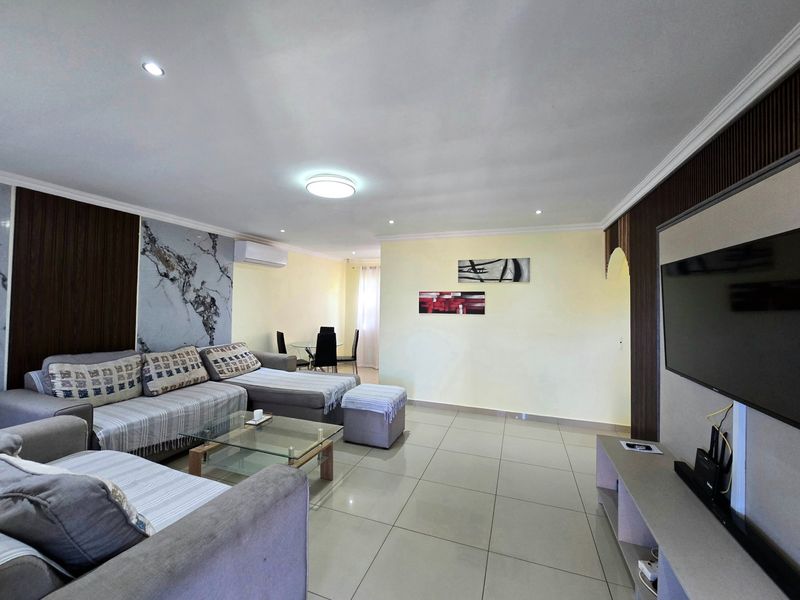 Spacious open-plan living area featuring tiled flooring, recessed lighting, and modern decorative wall paneling with an integrated air conditioning unit.