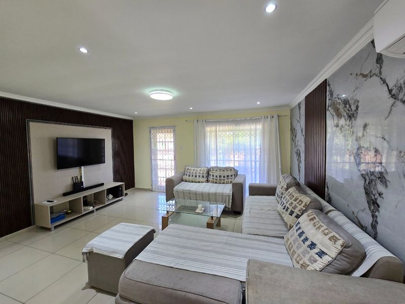 Spacious living room featuring modern tiled floors, decorative wall paneling, a marble-effect feature wall, and recessed lighting.