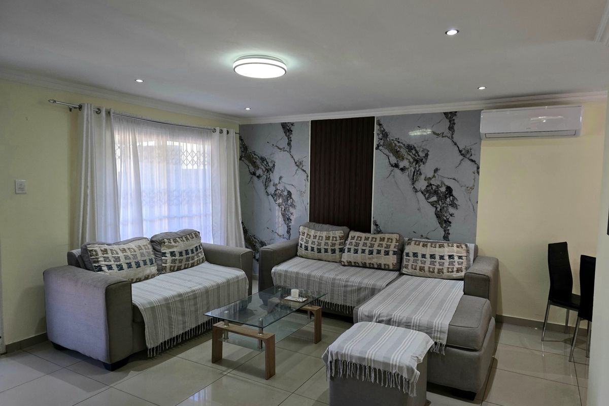 A well-maintained living room featuring tiled flooring, recessed lighting, a split-system air conditioner, and a decorative marble and timber slat feature wall.
