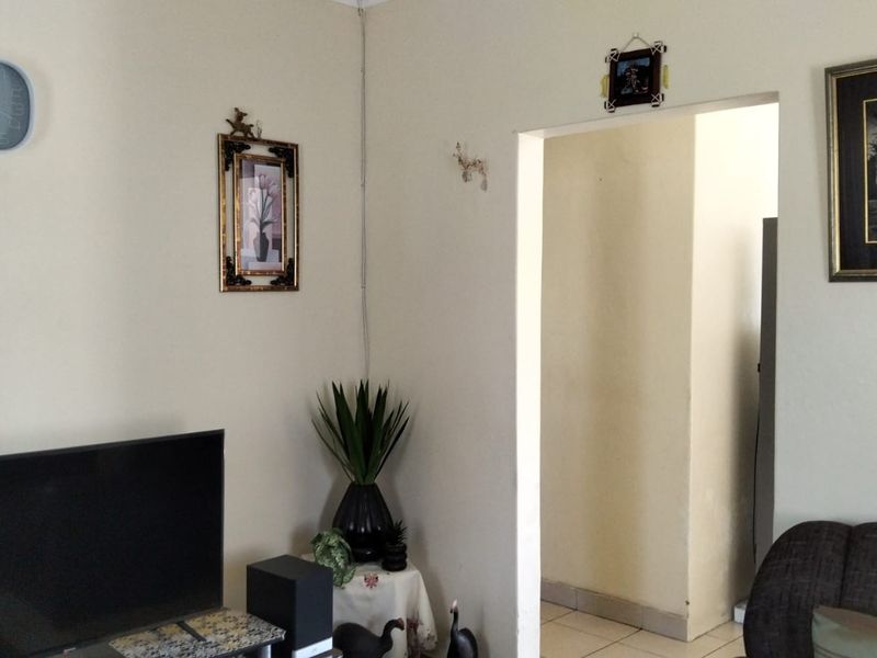A living room area featuring tiled flooring and a doorway leading to an adjacent space.