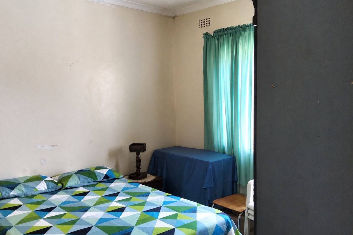 A bedroom featuring neutral walls with visible wear and a high-level air vent, providing a functional space ready for cosmetic updates.