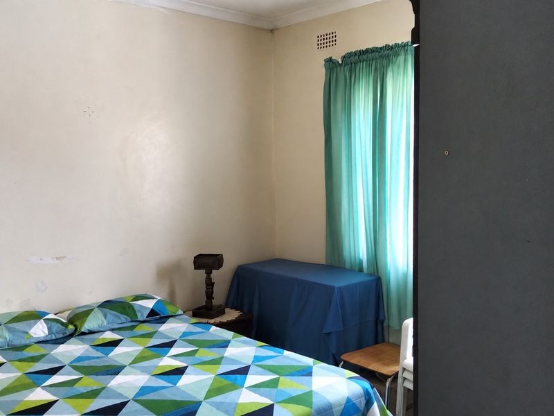 A bedroom featuring neutral walls with visible wear and a high-level air vent, providing a functional space ready for cosmetic updates.