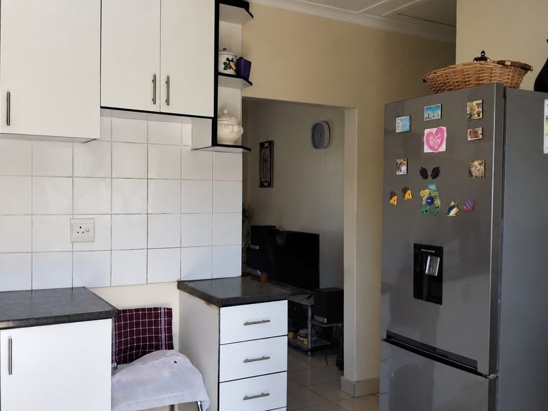 A functional kitchen area featuring white built-in cabinetry, dark laminate countertops, and a tiled backsplash, providing a practical workspace for daily meal preparation.