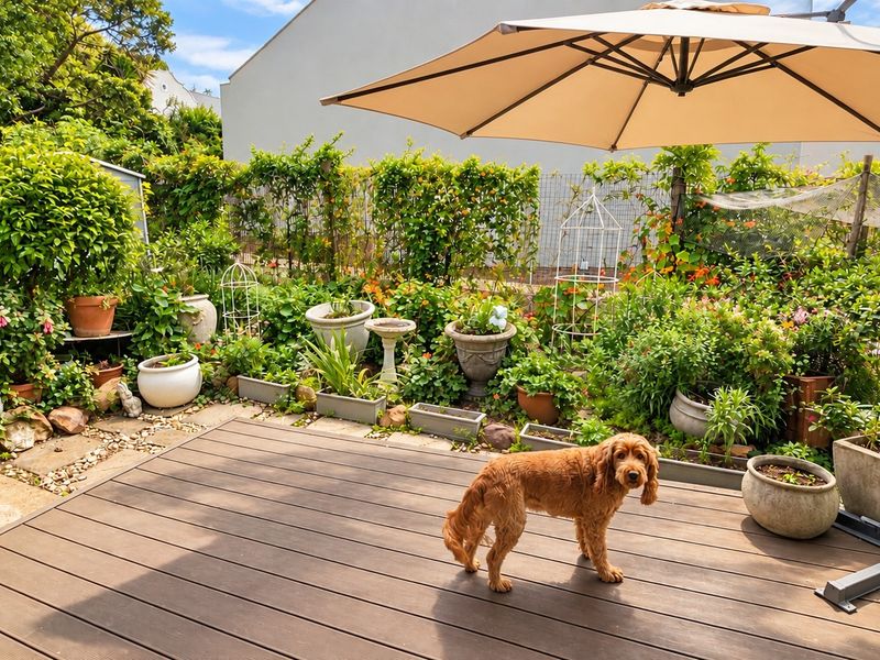 A well-maintained outdoor patio area featuring composite decking and a landscaped garden border with established greenery.