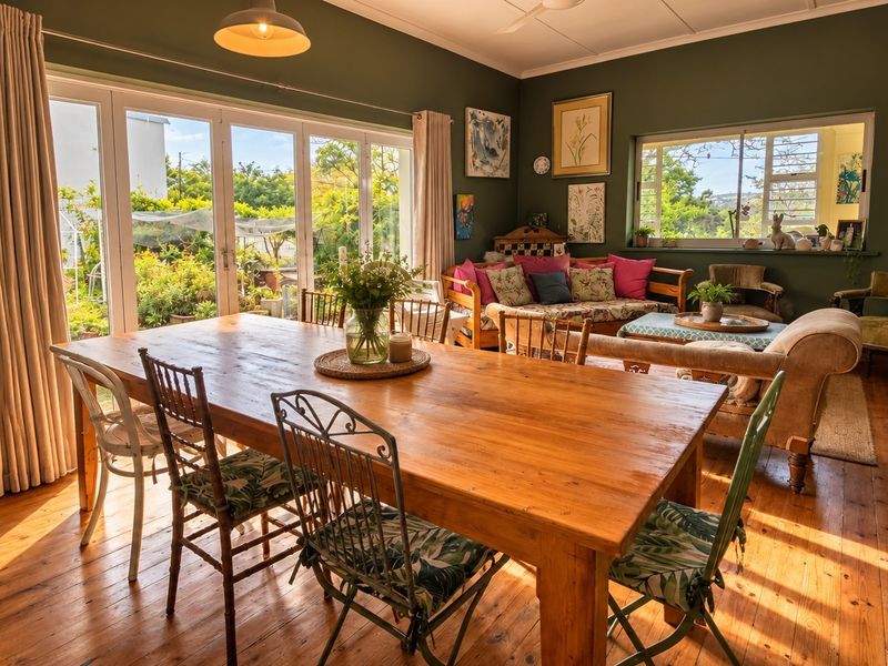 Spacious open-plan living and dining area featuring warm timber flooring, large sliding glass doors providing garden access, and abundant natural light.