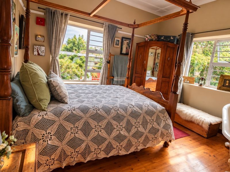 A bedroom featuring timber flooring, aluminium window frames, and a unique integrated freestanding bathtub within the sleeping area.