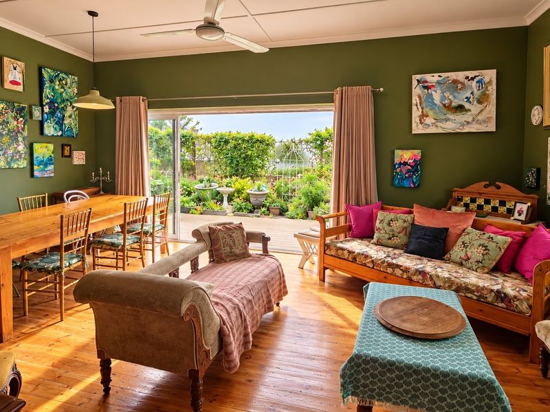 Spacious open-plan living and dining area featuring warm hardwood flooring, a ceiling fan, and large sliding doors opening to a garden patio.