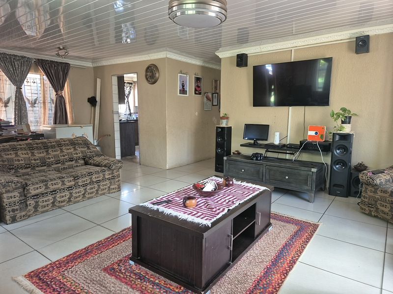 Spacious living room featuring tiled flooring, textured walls, and a glossy PVC ceiling, providing a functional and comfortable family living space.