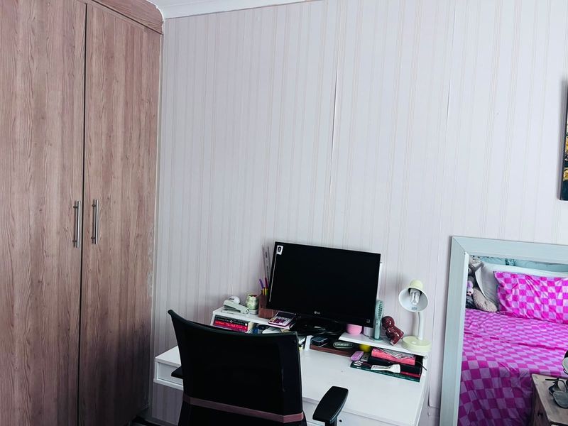 A bedroom featuring a wood-finish built-in wardrobe and decorative wall paneling, providing functional storage space.