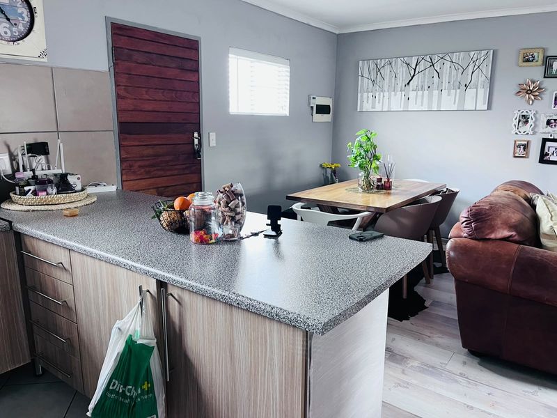 Open-plan living and kitchen area featuring a central island with laminate countertops, light wood-look cabinetry, and modern laminate flooring throughout.