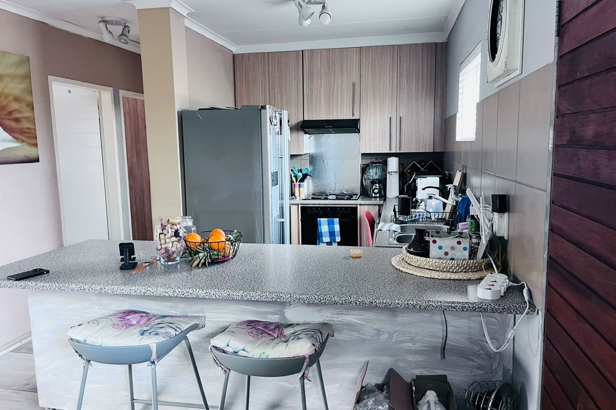A functional kitchen featuring wood-grain cabinetry, a granite-look breakfast bar, and built-in oven with extractor fan, offering a practical layout for daily use.