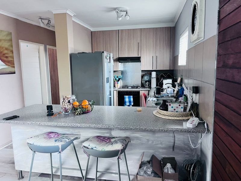 A functional kitchen featuring wood-grain cabinetry, a granite-look breakfast bar, and built-in oven with extractor fan, offering a practical layout for daily use.