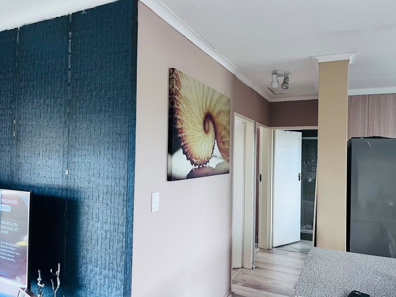 Open plan living area featuring textured feature wall, laminate flooring, and access to adjacent rooms via internal doors.