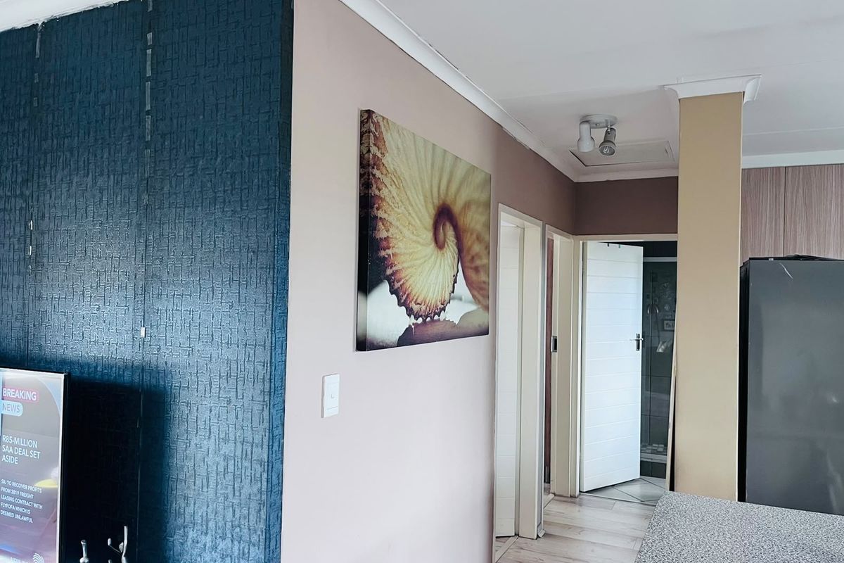Open plan living area featuring textured feature wall, laminate flooring, and access to adjacent rooms via internal doors.