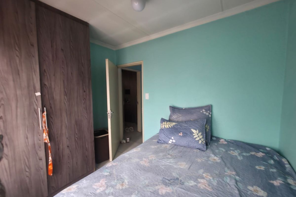 A bedroom featuring a built-in wardrobe with wood-grain finish and light blue painted walls.