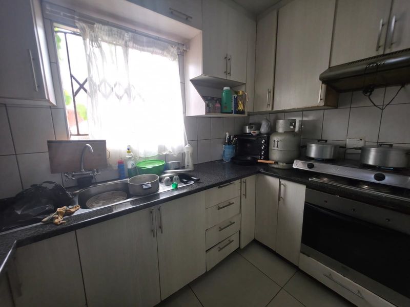 A functional kitchen featuring built-in cabinetry, granite countertops, a gas hob with extractor fan, and a tiled backsplash.