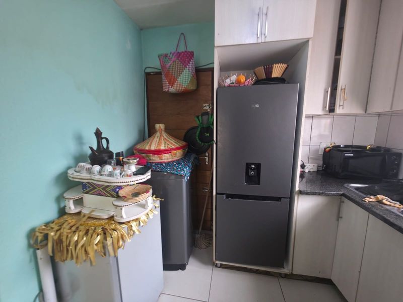 A compact kitchen area featuring built-in cabinetry, granite countertops, and a tiled backsplash, currently showing signs of wear and wall surface damage.