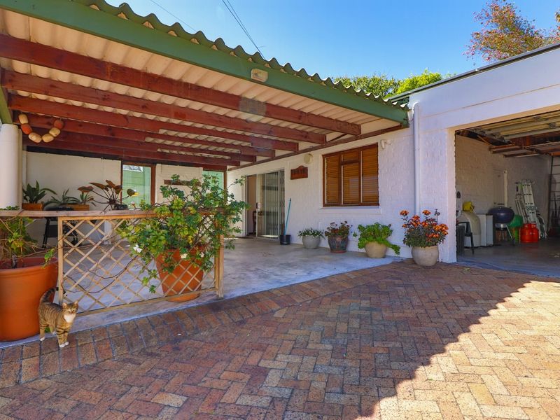 A covered patio area featuring a timber pergola, brick paving, and direct access to an attached garage.