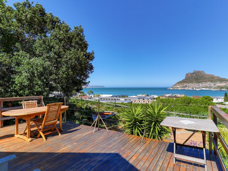 Spacious elevated timber deck featuring wire balustrades and panoramic coastal and mountain views.