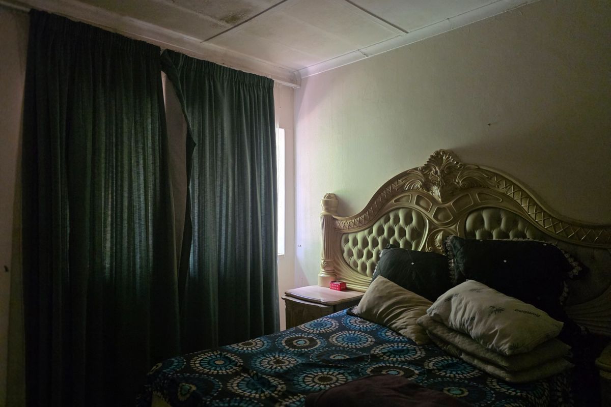 A bedroom featuring visible ceiling water damage and aging finishes, requiring maintenance and cosmetic updates to improve the overall condition.