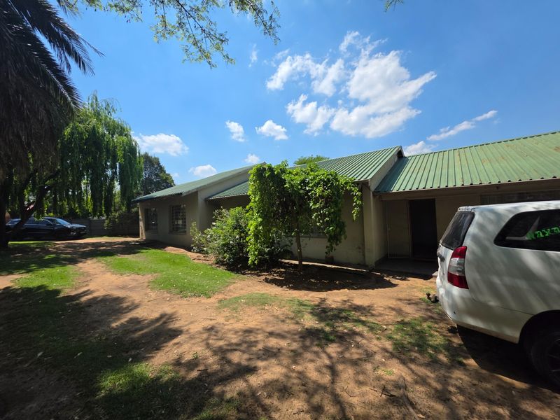 Rear view of the house featuring a corrugated metal roof, security entrance, and surrounding garden area.