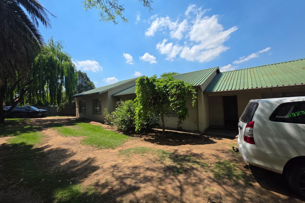 Rear view of the house featuring a corrugated metal roof, security entrance, and surrounding garden area.