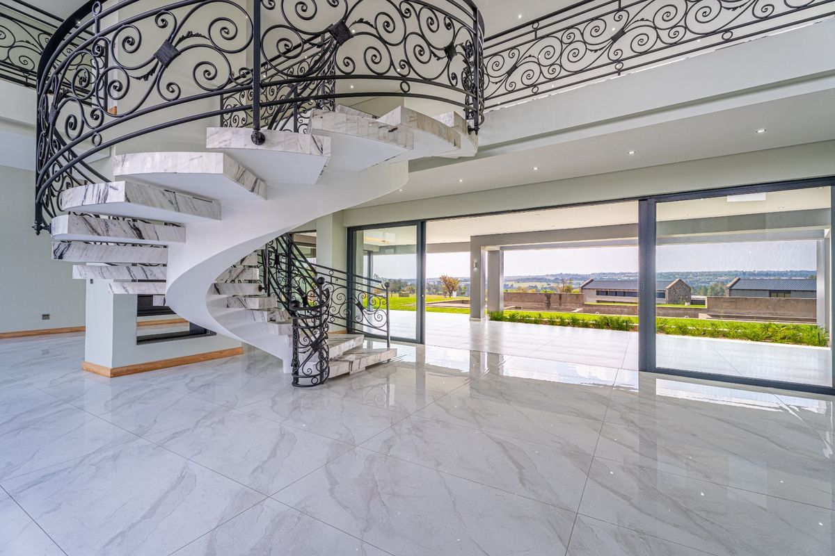 Spacious living area featuring a grand marble spiral staircase with wrought iron detailing, large format floor tiles, and seamless access to a covered patio.