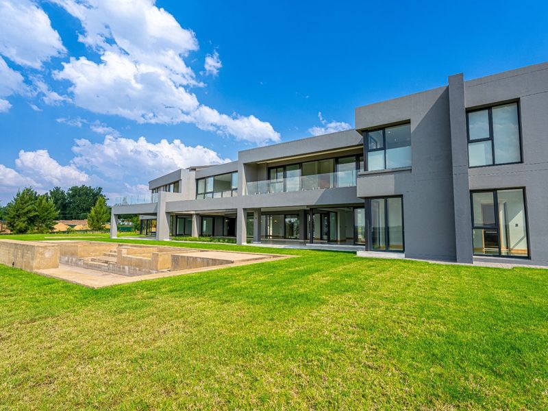Modern double-story rear elevation featuring expansive glass sliding doors, covered patio areas, and an unfinished concrete pool structure set within a large lawn.