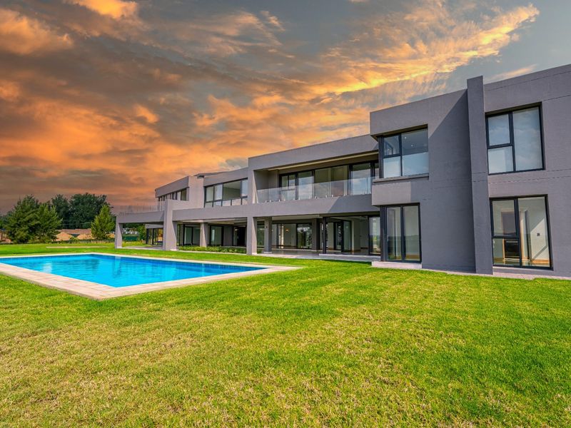 Modern double-story residence featuring a large swimming pool, expansive lawn, and extensive glass sliding doors opening onto a covered patio area.