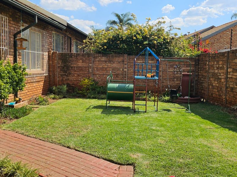 A private rear garden featuring a well-maintained lawn, brick paving, and secure perimeter walling with electric fencing.