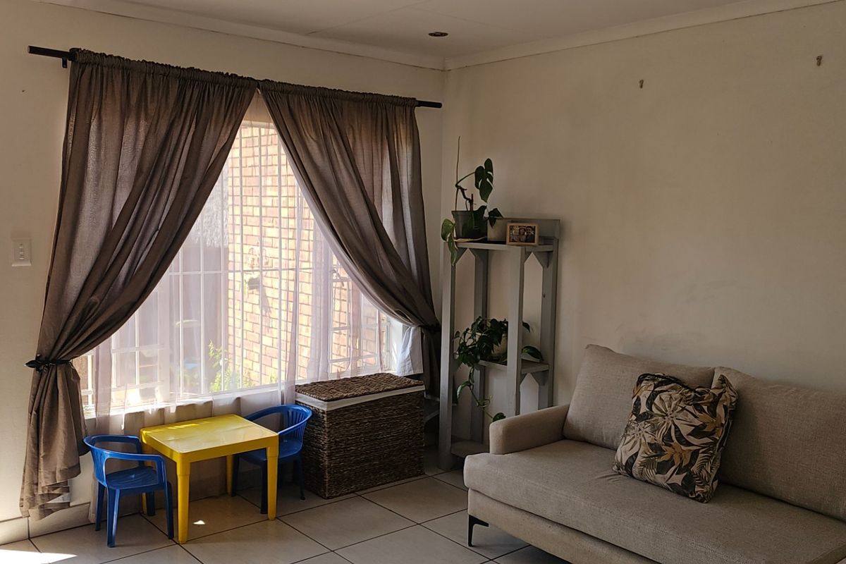 A living room featuring tiled flooring and a sliding door providing direct access to the garden area.