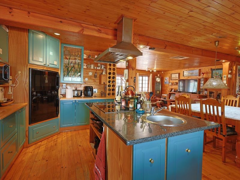 Spacious open-plan kitchen and dining area featuring warm timber finishes, a central island with granite countertops, and integrated cabinetry.