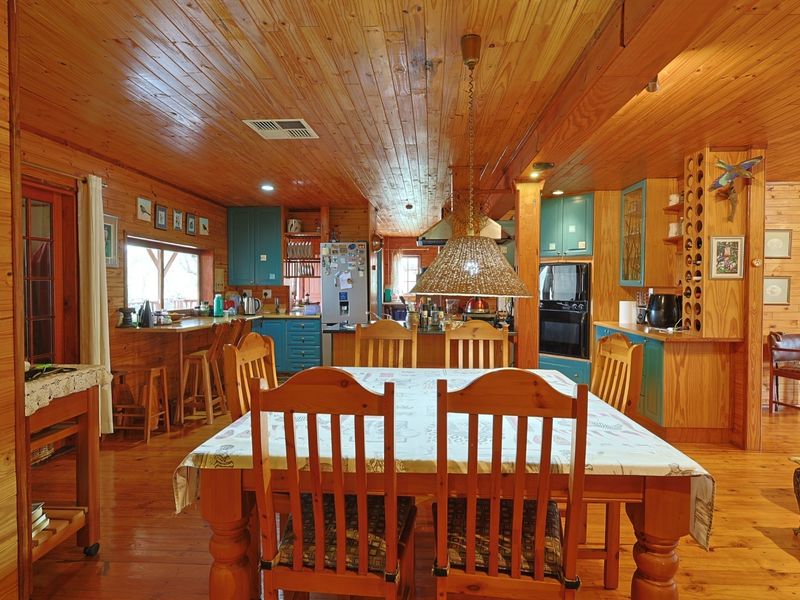 Open-plan kitchen and dining area featuring extensive timber wall and ceiling paneling, built-in cabinetry, and a breakfast bar.