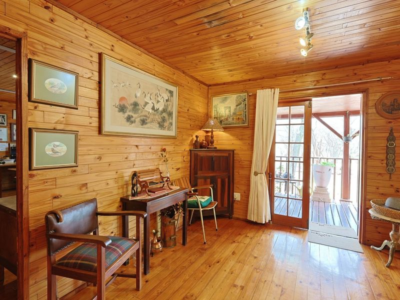 A living room featuring warm timber wall cladding, ceiling, and flooring, with direct access to an outdoor patio through a glass-paneled french door.