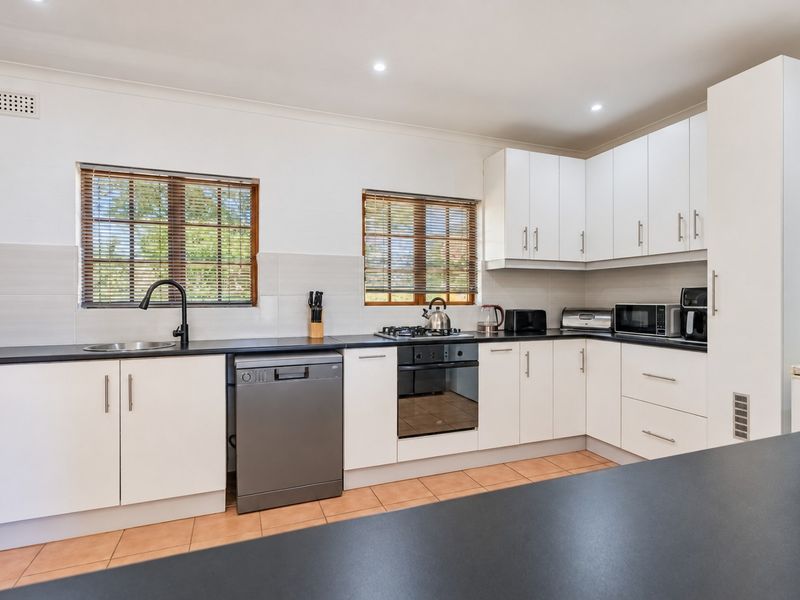 Modern kitchen featuring white cabinetry, black laminate countertops, integrated appliances, and tiled splashbacks, offering a clean and functional workspace.