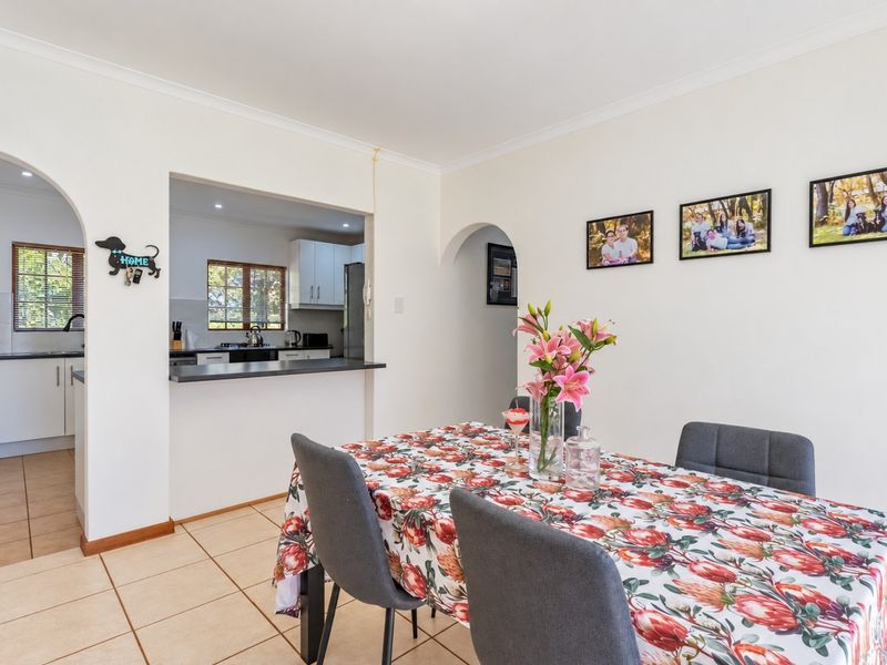 Open plan dining area featuring tiled flooring and an arched entryway leading to a functional kitchen with a breakfast bar.